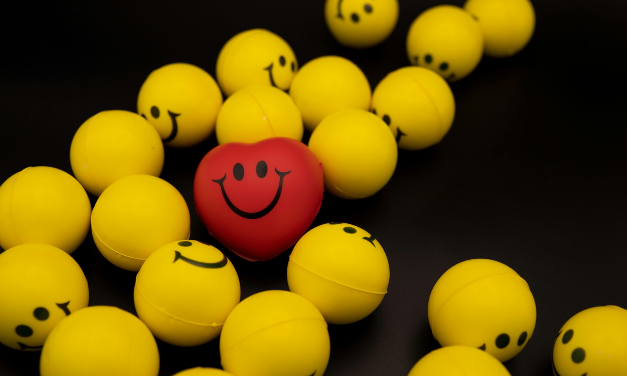 a smiling red heart nestled in a group of smiley yellow balls illustrating a happy heart with Gilbert's Syndrome